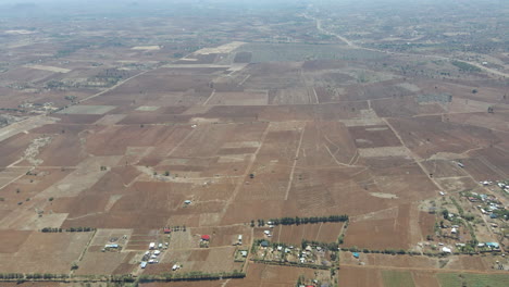 Panorámica-Aérea-Sobre-Pequeños-Asentamientos-Y-Revelando-Una-Ciudad-Distante-En-La-Zona-Rural-De-Kenia