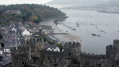 Historic-Conwy-castle-aerial-view-of-Landmark-town-ruin-stone-wall-battlements-tourist-attraction-descending-skyline-shot