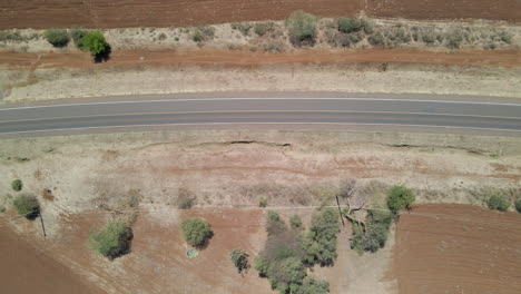 Top-down-aerial-of-power-lines-running-next-to-road-in-Kenya,-Africa