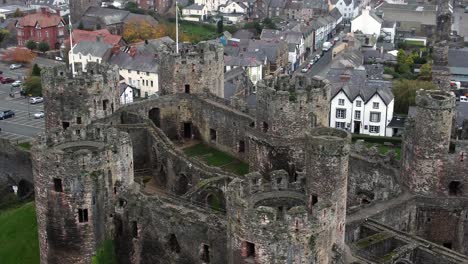 Historic-Conwy-castle-aerial-view-of-Landmark-town-ruin-stone-wall-battlements-tourist-attraction-close-Birdseye-tilt-down