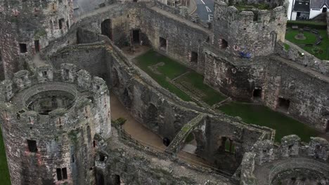 Historic-Conwy-castle-aerial-view-of-Landmark-town-ruin-stone-wall-battlements-tourist-attraction-Brirdseye-flyover-closeup-tilt-up