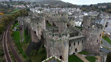 Historic-Conwy-castle-aerial-view-of-Landmark-town-ruin-stone-wall-battlements-tourist-attraction-push-in-descent-left
