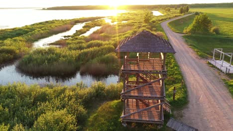 Girl-climbing-staircase-in-wetland-birding-hide-observation-tower-to-watch-golden-sunrise-aerial-shot