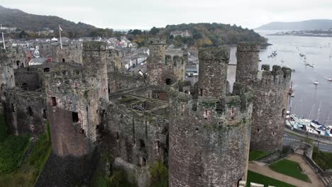 Historic-Conwy-castle-aerial-view-of-Landmark-town-ruin-stone-wall-battlements-tourist-attraction-close-descending-left