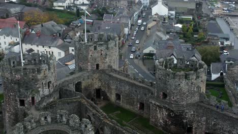 Historic-Conwy-castle-aerial-view-of-Landmark-town-ruin-stone-wall-battlements-tourist-attraction-Birdseye-pull-away-left