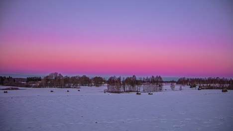 Time-lapse-shot-of-beautiful-purple-sky-and-sunrise-over-snowy-winter-field