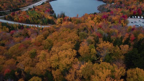 Aerial-of-blue-lake-in-the-mountains-surrounded-by-fall-foliage
