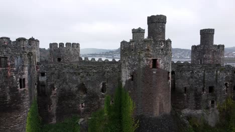 Historic-Conwy-castle-aerial-view-of-Landmark-town-ruin-stone-wall-battlements-tourist-attraction-descending-left-dolly