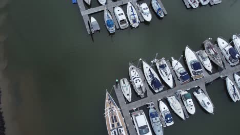 Top-down-aerial-drone-view-above-luxury-moored-private-marina-sailing-ships-and-yacht-boats-orbit-tilt-up-left-shot