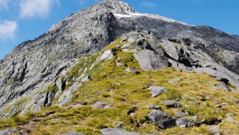 Tiro-Inclinado-Hacia-Arriba-De-Una-Maravillosa-Montaña-Rocosa-Y-Verde-Contra-El-Cielo-Azul-En-Verano---Caminata-De-Sillín-Gertrude-En-Nueva-Zelanda