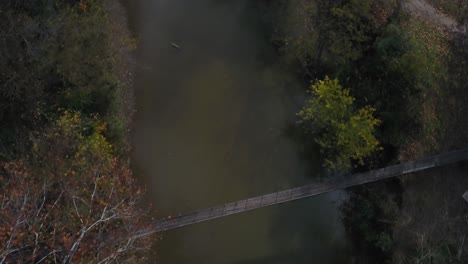 Drohnenaufnahme-Einer-Hängebrücke-über-Einen-Fluss-Im-Wald-Während-Der-Herbstsaison