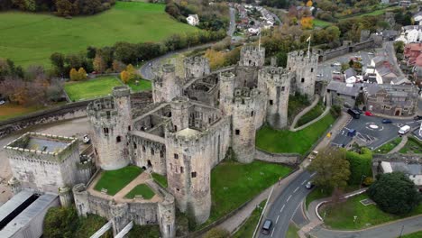 Historic-Conwy-castle-aerial-view-of-Landmark-town-ruin-stone-wall-battlements-tourist-attraction-pull-away-rising-closing-shot
