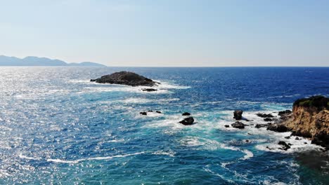 Beautiful-Turquoise-Waves-Hitting-Rocky-Cliffs-At-Jerusalem-Beach,-Erisos,-Greece---aerial-drone-shot