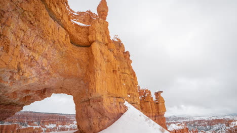 Bryce-Canyon-National-Park-Utah-USA,-Time-Lapse-of-Clouds-Moving-Above-Snow-Capped-Rock-Formations-and-Natural-Arch