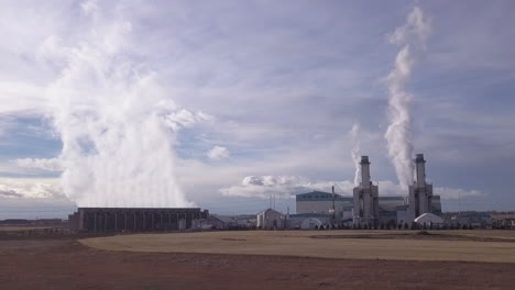 Hot-steam-escapes-electrical-power-plant-turbines-against-big-dark-sky