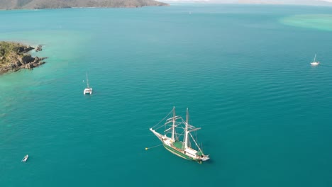 Sailing-ship-sails-in-a-wonderful-crystal-clear-sea,-aerial-view-from-drone