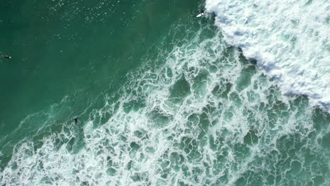 4k-Drone-zoom-out-shot-of-people-surfing-in-Lennox-Head,-Australia