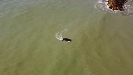 Aerial-tracking-shot-of-black-inflatable-boat-cruising-back-to-coast-of-Mar-del-Plata-during-summer,Argentina