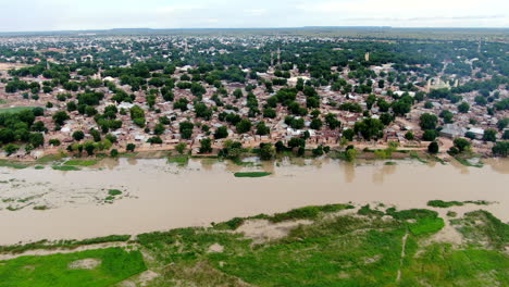 The-swollen-Sokoto-river-in-Argungu-Town-in-the-Kebbi-State-of-Nigeria---sliding-aerial-view-of-the-flooded-shoreline