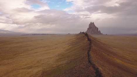 Drone-shot-panning-to-the-right-flying-over-the-large-ridge-looking-over-the-western-landscape-around-Shiprock,-Navajo-New-Mexico,-USA-in-4k