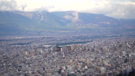 Panorama-Interminable-Del-Paisaje-Urbano,-Edificios-De-La-Ciudad-De-Atenas-Con-Nubes-Pesadas-En-Las-Montañas