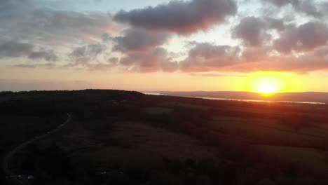 Aerial-shot-looking-towards-Exmouth-in-Devon-England-from-Woodbury-Common-over-a-busy-road-and-with-a-beautiful-golden-sunset