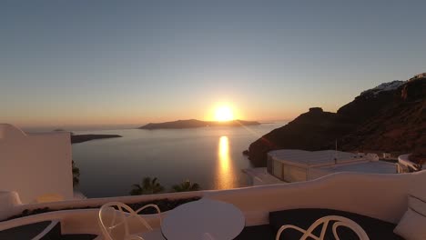Epischer-Sonnenuntergang-Im-Zeitraffer-Vom-Typischen-Santorini-Balkon,-Sonnenreflexion-Auf-Dem-Wasser