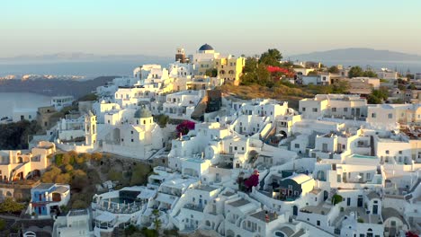 Aerial-view-Imerovigli-village-sits-on-a-clifftop-lit-by-First-morning-Lights,-Santorini