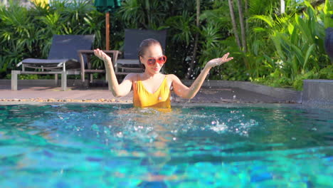 Beautiful-Asian-traveler-girl-having-fun-inside-swimming-pool-at-a-tropical-hotel-in-Bali