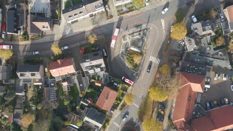 Top-down-aerial-of-bus-leaving-small-busstation-in-a-small-town-in-autumn