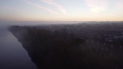 Misty-Autumn-dense-fog-over-Manchester-ship-canal-aerial-view-across-houses-landscape