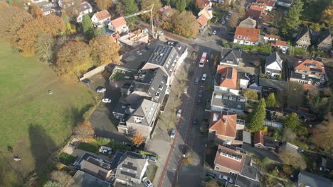 Aerial-of-bus-driving-over-street-in-a-small-town-in-autum