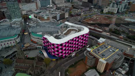 Push-in-aerial-shot-over-the-famous-landmark-of-the-Bull-Ring-shopping-mall-in-Birmingham-England
