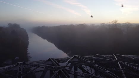 Misty-Autumn-Manchester-ship-canal-aerial-view-pull-back-over-Wilderspool-causeway-cantilever-arched-bridge