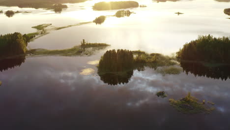 Drone-point-of-interest-shot-circling-around-uninhabited-small-islands-on-a-calm-lake-by-sunset-golden-hour