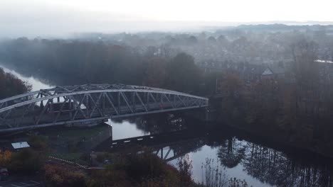 Misty-Autumn-Wilderspool-causeway-cantilever-bridge-over-Manchester-ship-canal-aerial-view-zoom-in
