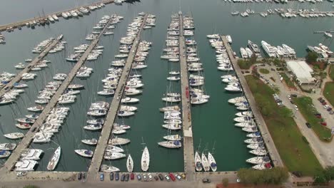 Flight-over-the-yacht-marina-filled-with-modern-sailboats,-aerial-shot,-camera-moves-to-the-left