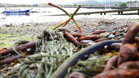 Rusted-algae-covered-anchor-and-chains-on-low-tide-Welsh-harbour-seafront-dolly-left