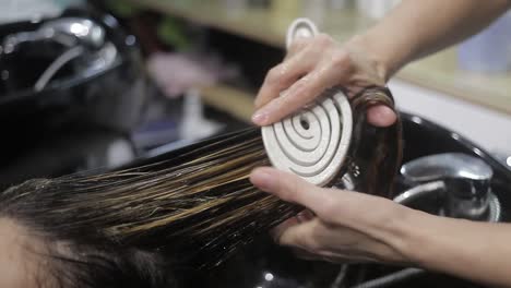 Stylist-combs-and-cleans-client's-hair-in-beauty-salon
