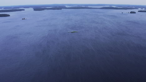 Drone-shot-of-vast-open-water-area-with-a-small-islet-in-the-middle-on-a-windy-evening