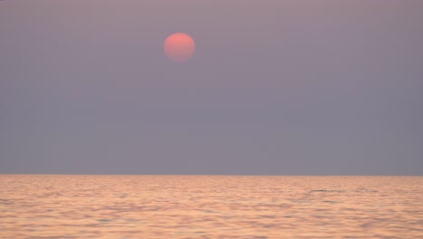 Beautiful-Setting-sun-at-the-sea-horizon,-Boat-crossing-on-idyllic-sunset-colors,-Crete