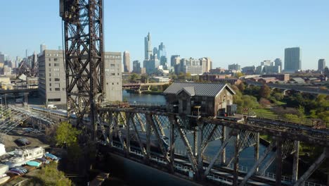 Fixed-Aerial-View-of-Train-Crossing-Bridge-in-Chicago,-Skyline-in-Background