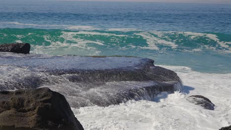 Meerwasser-Spült-über-Einen-Großen-Felsen,-Während-Sich-Eine-Neue-Welle-Bildet