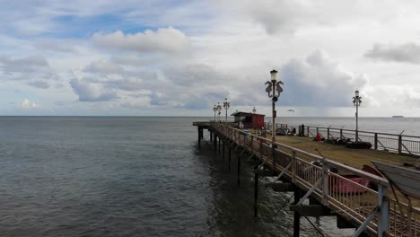 Aerial-Flying-Beside-Teignmouth's-Grand-Pier-Reaching-Out-In-The-English-Channel