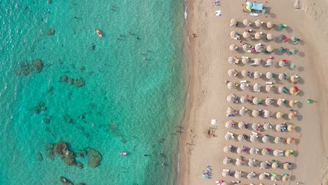 Top-down-shot-pristine-turquoise-water-with-submerged-rocks-and-Umbrellas,-Falassarna-beach