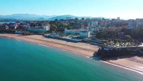 European-beach-close-to-the-city,-with-blue-waters-and-mountains-in-the-background
