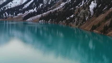 Wide-drone-shot-of-the-turquoise-colored-lake-water-at-Big-Almaty-Lake-in-the-Trans-Ili-Alatau-mountains-in-Kazakhstan