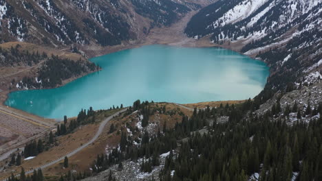 Cinematic-revealing-drone-footage-of-the-Big-Almaty-Lake-starting-on-the-forest-then-tilting-up,-in-the-Trans-Ili-Alatau-mountains-in-Kazakhstan