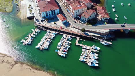 Small-harbour-with-sport-boats-and-people-strolling-on-the-promenade-in-San-Vicente-de-la-Barquera,-Cantabria,-Spain-on-a-beautiful-sunny-day