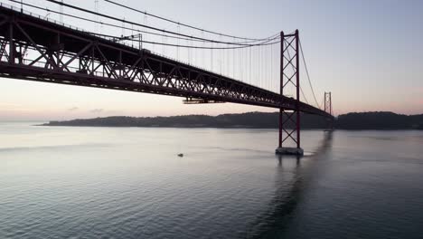 Small-boat-underneath-the-suspension-bridge-in-Portugal